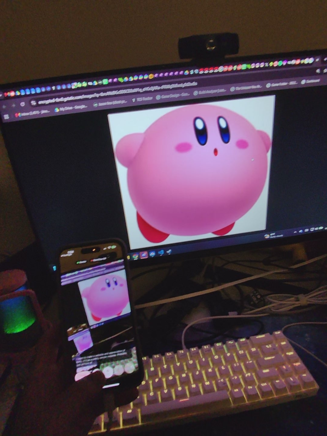 Kirby displayed on a monitor and phone in a desktop setup